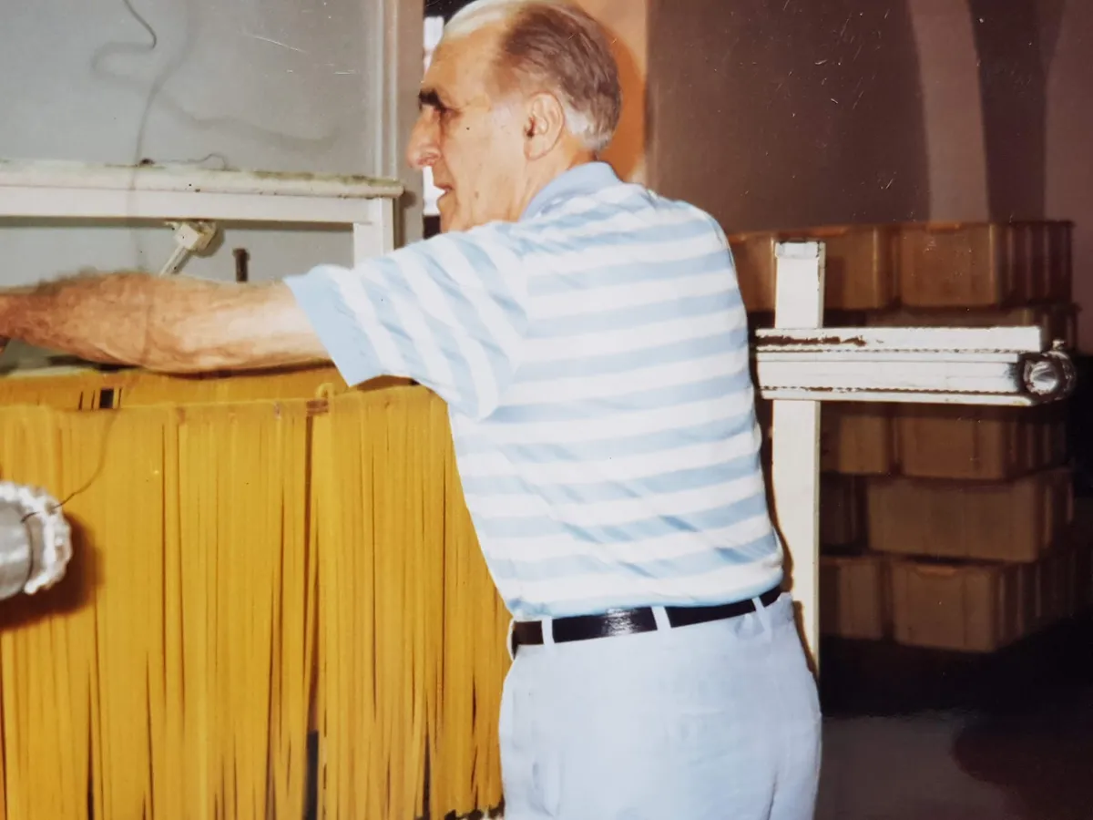 마리오 파엘라 — 건조대 앞에서 파스타를 다루는 모습